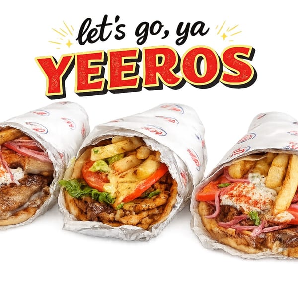 Three Greek yeeros, filled with meat, fries, vegetables, and sauce, wrapped in paper.